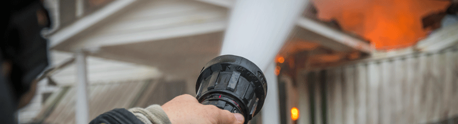 A fireman is holding a fire hose to put out fire.