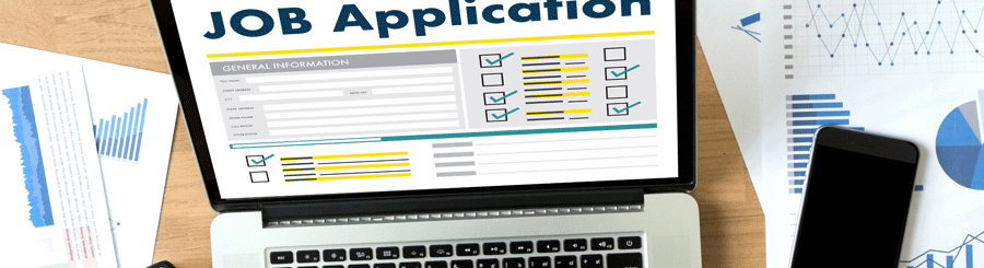 A person is holding an iPhone and a laptop in front of him searching a job and filing applications.